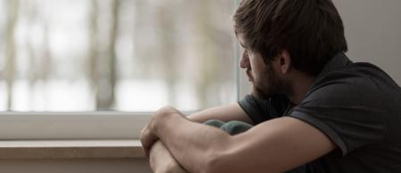 Reflective young man with a beard stares out window